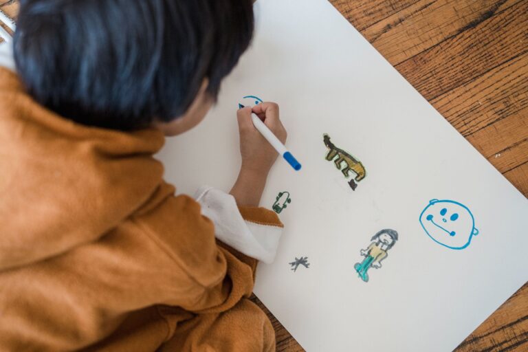 A child creating drawings with markers on paper while sitting indoors.