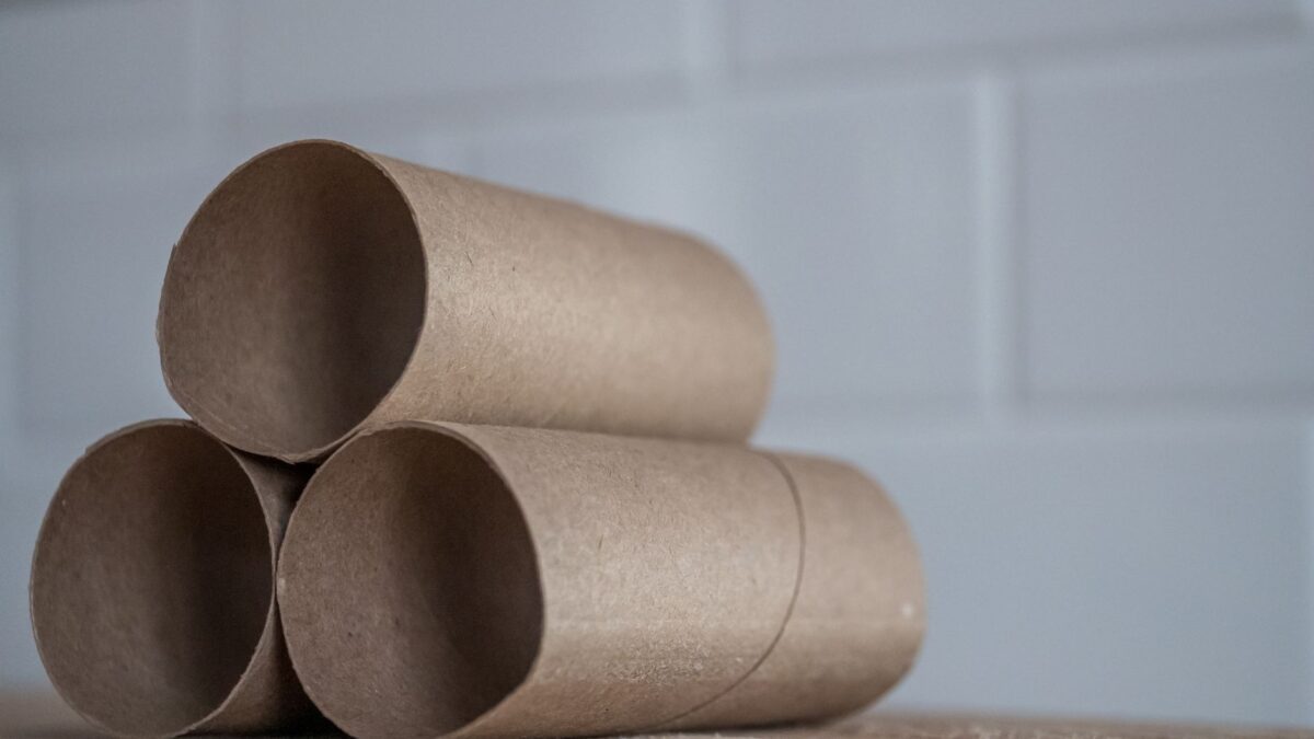 Closeup of stacked brown cardboard tubes of finished toilet paper placed on wooden table