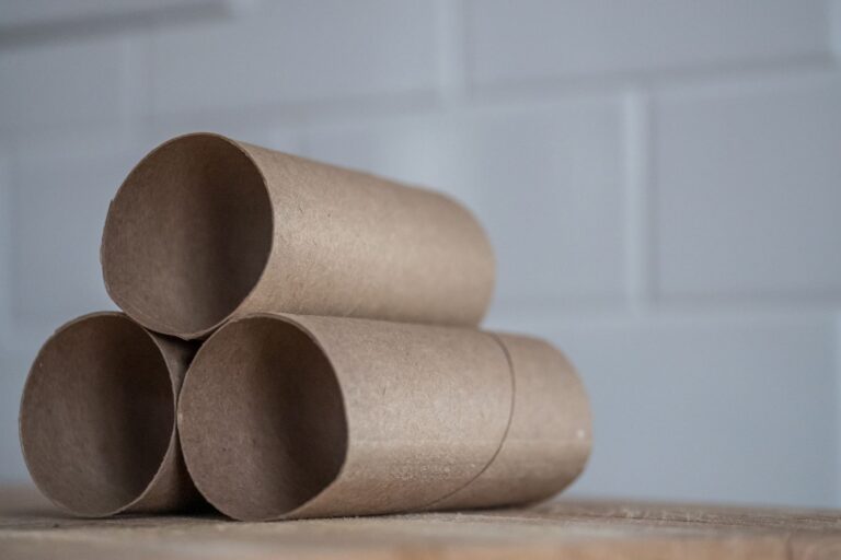 Closeup of stacked brown cardboard tubes of finished toilet paper placed on wooden table